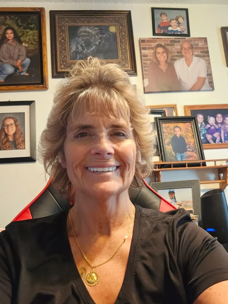 Smiling woman in room with family photos.
